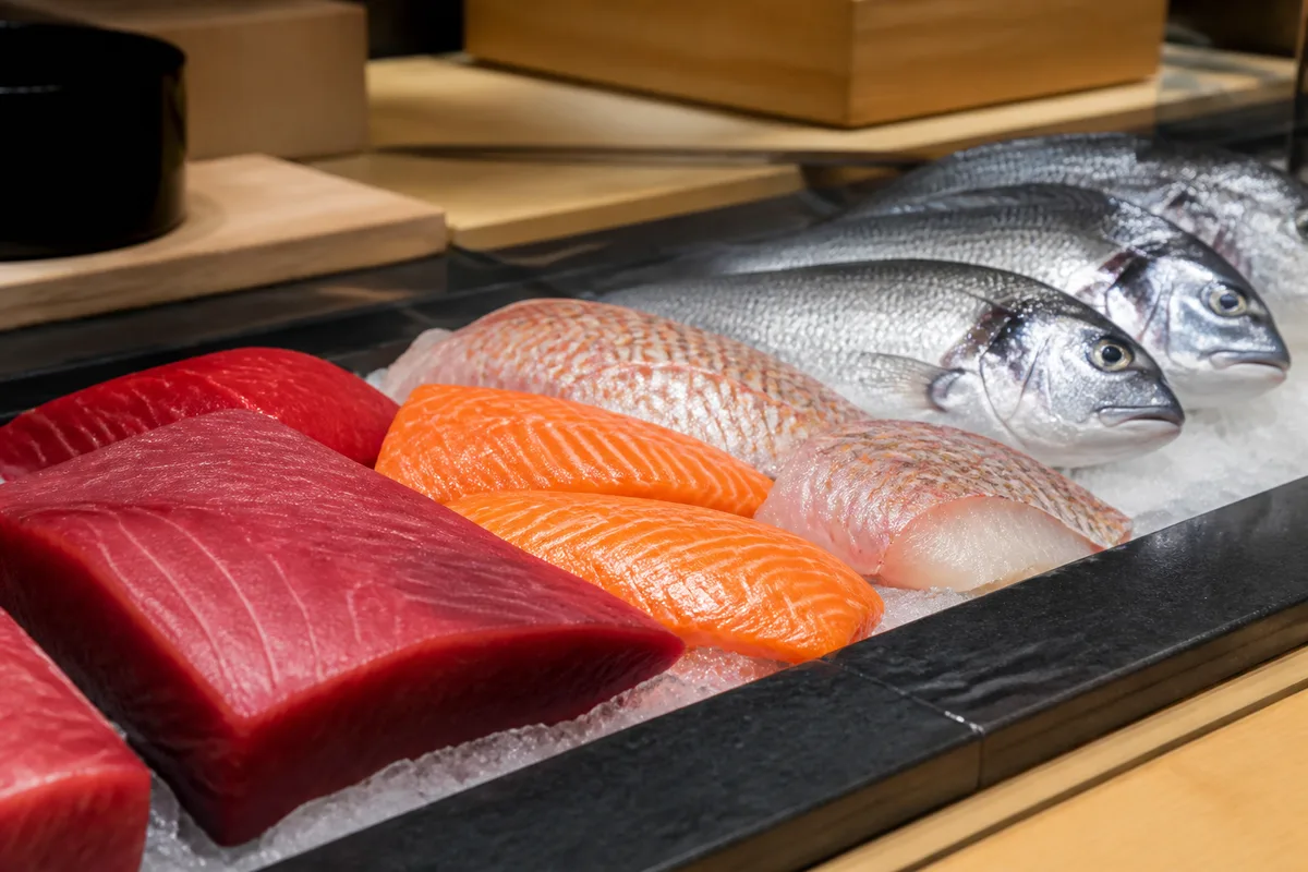 Étal de poissonnerie présentant thon, saumon et daurade destinés à la découpe